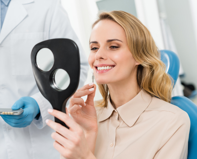 Woman holding black dental mask model in modern dental office with dentist in background