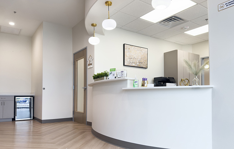 Modern dental office reception area with curved white desk and bright, clean interior design.