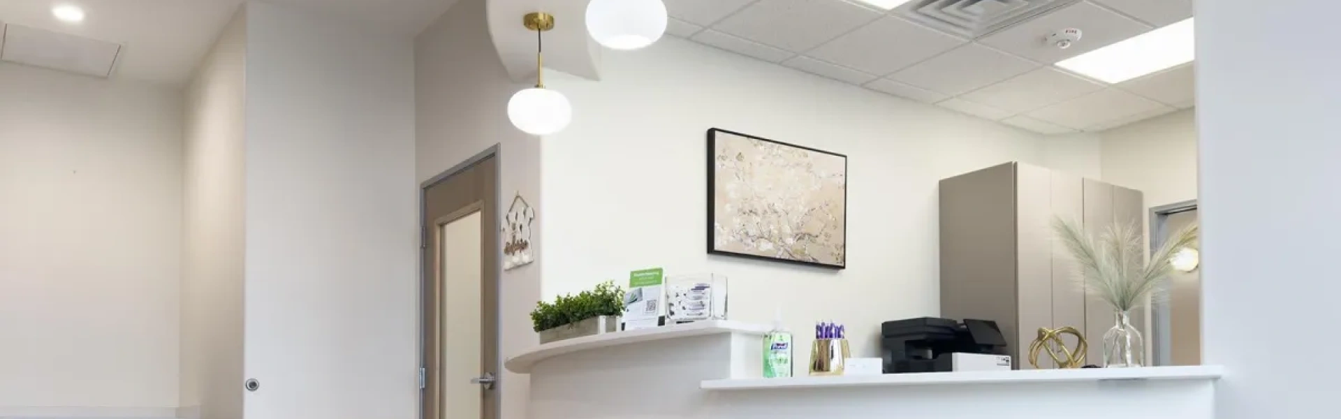 Modern dental office reception area with white walls, counter desk, and professional healthcare setting.