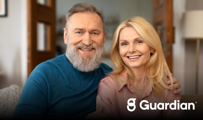 Smiling couple in casual clothing poses together indoors for dental wellness practice portrait.